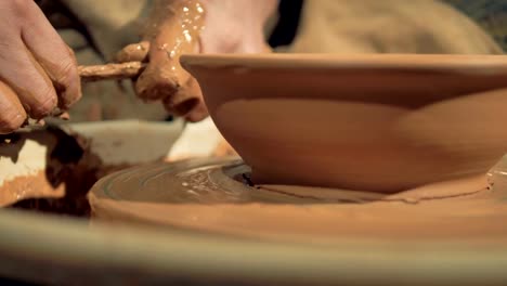 A-detailed-view-on-potters-hands-cutting-away-excess-clay-from-a-bowl.