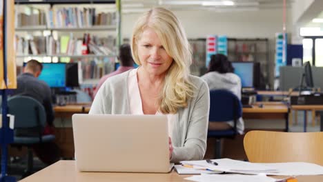 Reife-Studentin-arbeiten-am-Laptop-In-der-Universitätsbibliothek