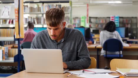 Masculino-estudiante-trabajando-en-ordenador-portátil-en-la-biblioteca-de-la-Universidad