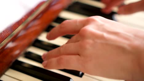 Female-fingers-playing-keys-on-retro-piano-keyboard.-Shallow-depth-of-field.-Focus-on-hands