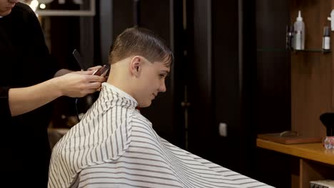 Barber-cuts-guy's-hair-with-electric-razor-in-barbershop