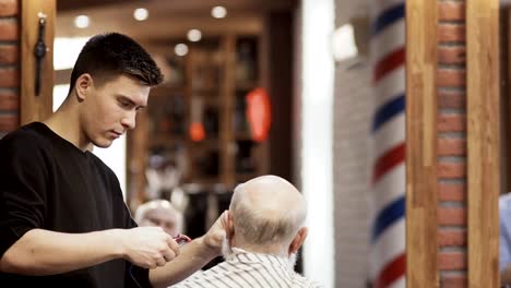 Friseur-rasiert-graues-Haar-von-reifer-Mann-im-barbershop