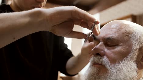 Friseur-schneidet-Brauen-des-älteren-Menschen