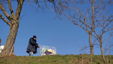 Niedrigen-Winkel-Ansicht-von-Obdachlosen-Mann-schieben-Karren