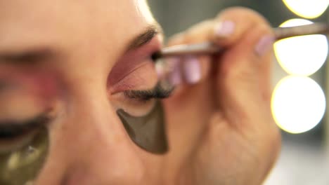 Make-up-artist-applying-eye-shadow-to-model's-eye.-Close-up-view.-Patches