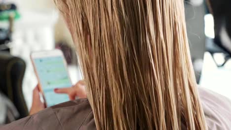 Male-hairdresser-combing-hair-to-blonde-girl-in-beauty-salon,-close-up