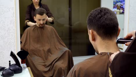 Hairdresser-cuts-hair-of-man-with-electric-razor