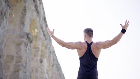 Famous-sportsman-with-strong-defined-muscles-posing-in-front-of-a-camera-on-the-background-of-ruines