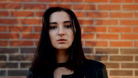 Portrait-of-a-young-serious-sexy-woman-against-a-brick-wall.-Slow-motion-shot.