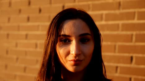 Portrait-of-a-young-serious-sexy-woman-against-a-brick-wall.-Slow-motion-shot.