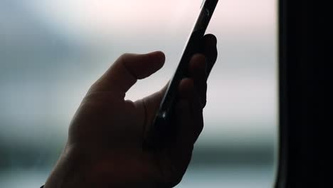 Cellphone-device-while-on-a-moving-train.-Close-up-of-hands-holding-smartphone-checking-emails-and-surfing-the-internet-while-on-commute