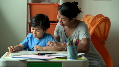 Kinder-Hausaufgaben.-Junge-Mischlinge-junge-Hausaufgaben-auf-der-Terrasse-zu-Hause.-Lesebuch-mit-seiner-Mutter.-Gute-Laune.-Zurück-zum-Schulkonzept.