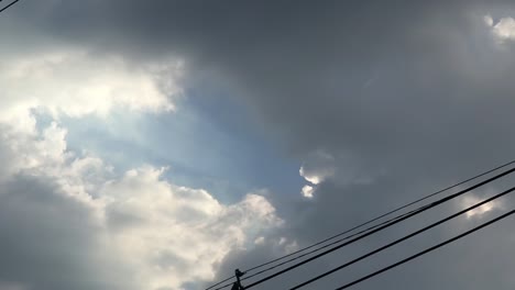 Gray-overcast-clouds-on-blue-sky-before-rain-or-storm.-Electrical-power-lines-pass-through-the-sky.