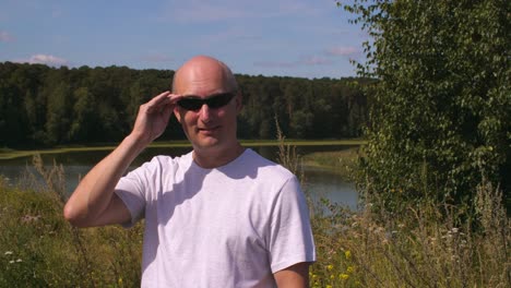 Gut-aussehender-Mann-in-Sonnenbrille-lächelnd-und-unter-Ausschluss-der-Öffentlichkeit-im-Sommer-Wald