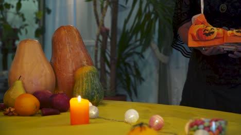 Halloween.-Young-witch-carries-a-basket-of-sweets-on-the-table