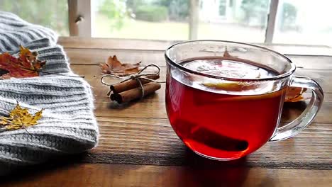 Té-en-la-mesa-de-madera-con-la-decoración-de-otoño-cerca-de-una-ventana-con-zoom-en-cámara-lenta