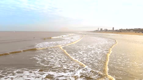 Luftaufnahme.-Slow-Motion-Flug-über-das-Meer-und-die-Wellen,-die-kommen-zum-Ufer-in-den-sonnigen-Morgen.-Niederlande-Zandvoort.-Nordsee.-Uferlinie