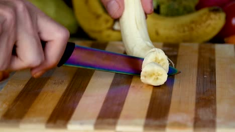 Man-is-cutting-banana-on-cutting-board,-close-up-footage