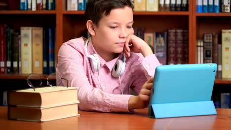cute-schoolboy-using-computer-tablet-and-listening-to-it-lecture.