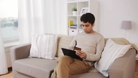 Mann-mit-TabletPC-und-Kreditkarte-zu-Hause-auf-sofa