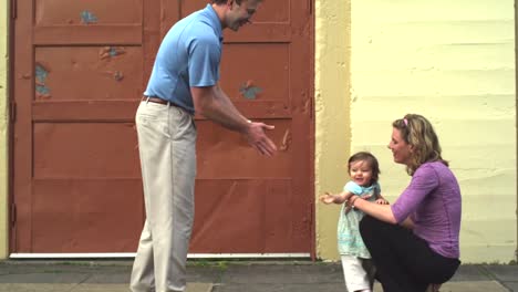 A-mother-and-father-help-their-young-daughter-walk-down-the-street