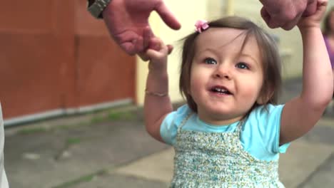 A-happy-smiling-baby-girl-walks-down-the-street-with-the-help-of-an-adult