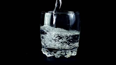 Wasser-in-einem-Glas-auf-einem-schwarzen-Hintergrund.-Slow-Motion.