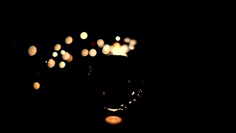 Burning-sparkler-behind-a-glass-ball-on-a-black-background.