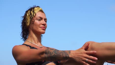 Mujer-haciendo-fitness-en-la-playa-con-arena-negra-volcánica-en-un-traje-de-baño-sentado-en-una-roca-en-las-montañas-de-lava.-El-concepto-de-estilo-de-vida-saludable-y-la-recreación-en-las-islas