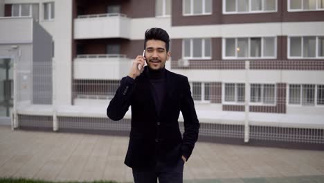 Young-handsome-businessman-walking-and-talking-on-mobile-phone-in-the-city