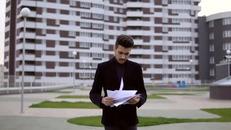 Young-businessman-walking-and-throw-out-documents-against-business-building-background