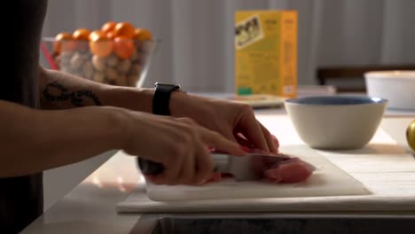 Close-up-woman-cuts-chicken-with-a-knife-on-a-Board.-Female-hands-chef-cutting-raw-chicken-meat-breast.