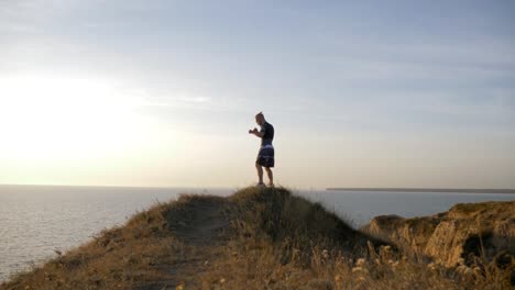 sports-training-on-open-air,-muscular-pugilist-male-practicing-boxer-punches-before-sparring-on-workout-on-hill-near-sea