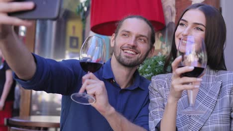 Feliz-pareja-con-vino-tomando-fotos-en-el-teléfono-en-el-restaurante