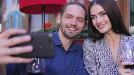 Feliz-pareja-con-vino-tomando-fotos-en-el-teléfono-en-el-restaurante