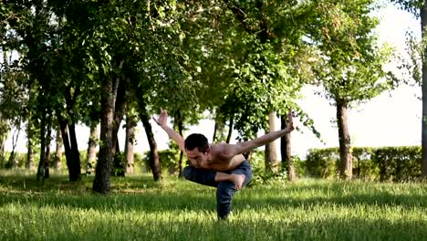 Brunette-guy-doing-yoga-moves-on-green-grass.