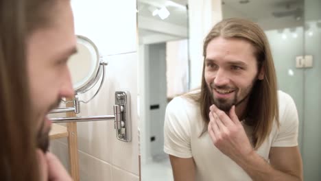 Bathroom.-Man-Looking-In-Mirror-And-Touching-Face