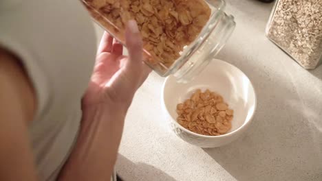 Desayuno-saludable.-Manos-de-mujer-llenando-el-tazón-de-fuente-de-Muesli-de-cereales