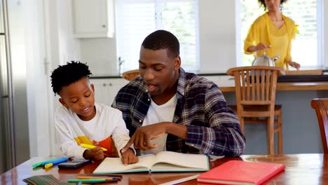 Front-view-of-black-father-helping-his-son-with-homework-at-comfortable-home-4k