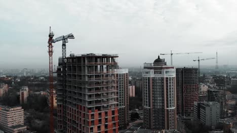 Aerial-view-of-high-rise-concrete-building-construction.-Residential-complex-construction-in-big-metropolis.-Drone-flying-near-unfinished-brick-building