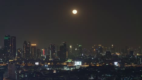 Aerial-view-of-Sathorn-with-the-full-moon,-Bangkok-Downtown,-Thailand.-Financial-district-and-business-centers-in-smart-urban-city-in-Asia.-Skyscraper-and-high-rise-buildings-at-night.