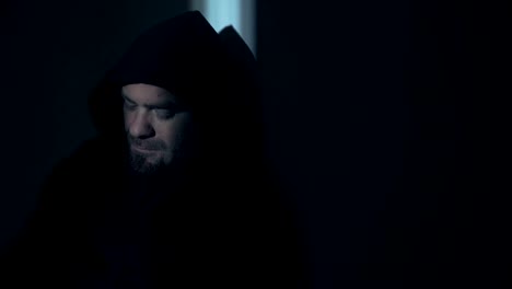 Portrait-of-sad--thoughtful-hooded-young-man-in-darkness