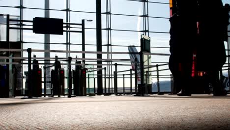 Siluetas-de-personas-caminando-por-las-puertas-en-el-terminal-del-aeropuerto,-vuelo,-vista-inferior