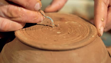 A-detailed-view-on-a-potter-cutting-his-signature-on-a-bowls-bottom-surface.