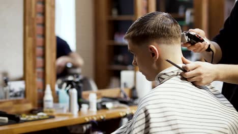 Stylist-makes-modern-hairstyle-for-young-guy-in-barbershop