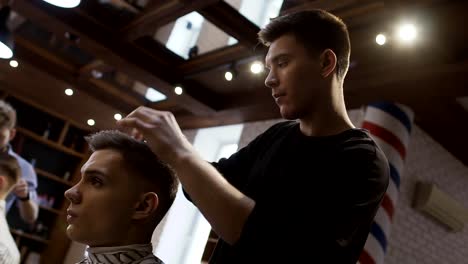 Professional-stylist-makes-hair-styling-for-young-man-in-barbershop