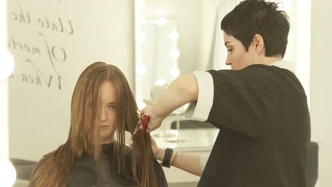 Weibliche-Friseur-Aufsprühen-von-Wasser-auf-das-Haar-beim-Schneiden-im-Friseursalon.-Friseur,-Schönheitssalon-weiblichen-Haarschnitt-bei-hautnah