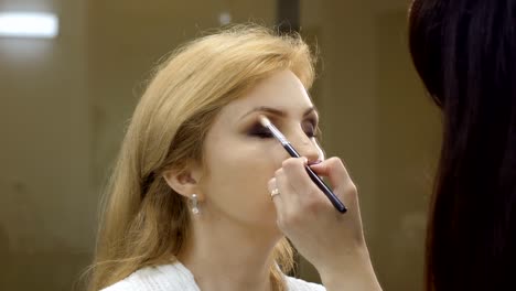 Artista-de-maquillaje-prepara-a-mujer-adulta-a-la-etapa,-sala-de-maquillaje