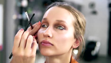 Studio-machen.-Professionelle-Make-up-Künstler-machen-sich-für-ein-schönes-kaukasischen-Modell-zu-tun.-Einige-Lidschatten-mit-einem-Pinsel-auftragen.-Augen-Make-up