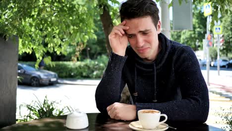 Portrait-of-Crying-Sad-Young-Man-Sitting-in-Cafe-Terrace